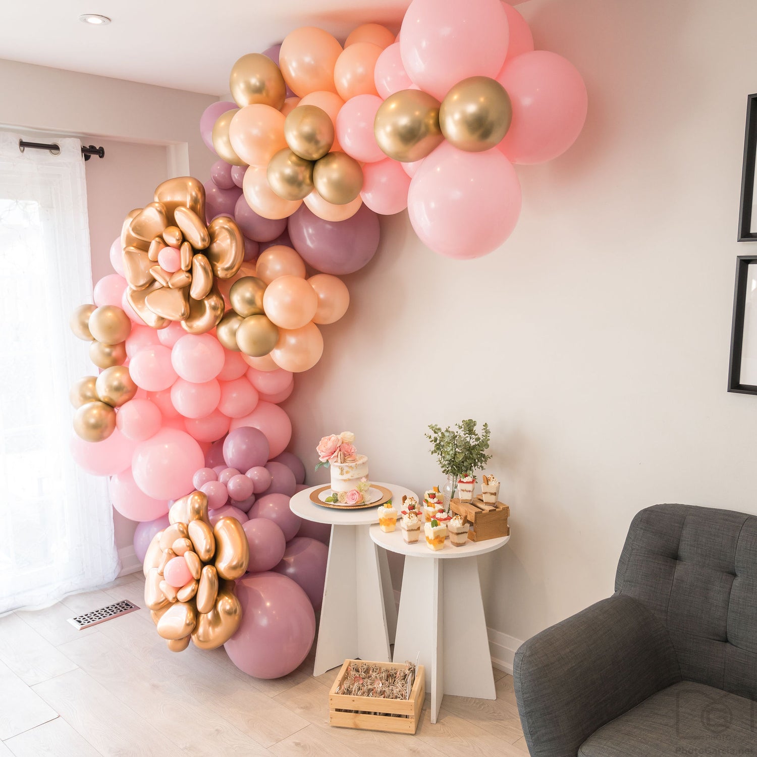 Pink, purple and gold balloon garland decorating a wall.