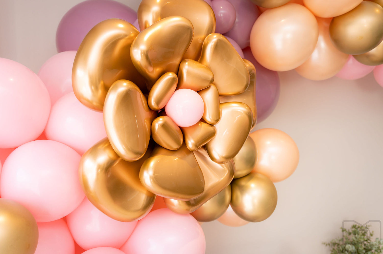 Gold flower made of balloons surrounded by pink and purple balloons.k